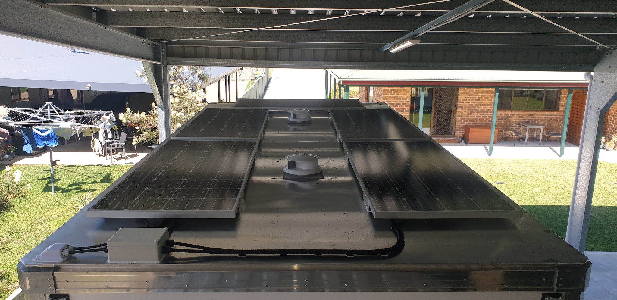 Four solar panels and two roof vents installed across a caravan roof